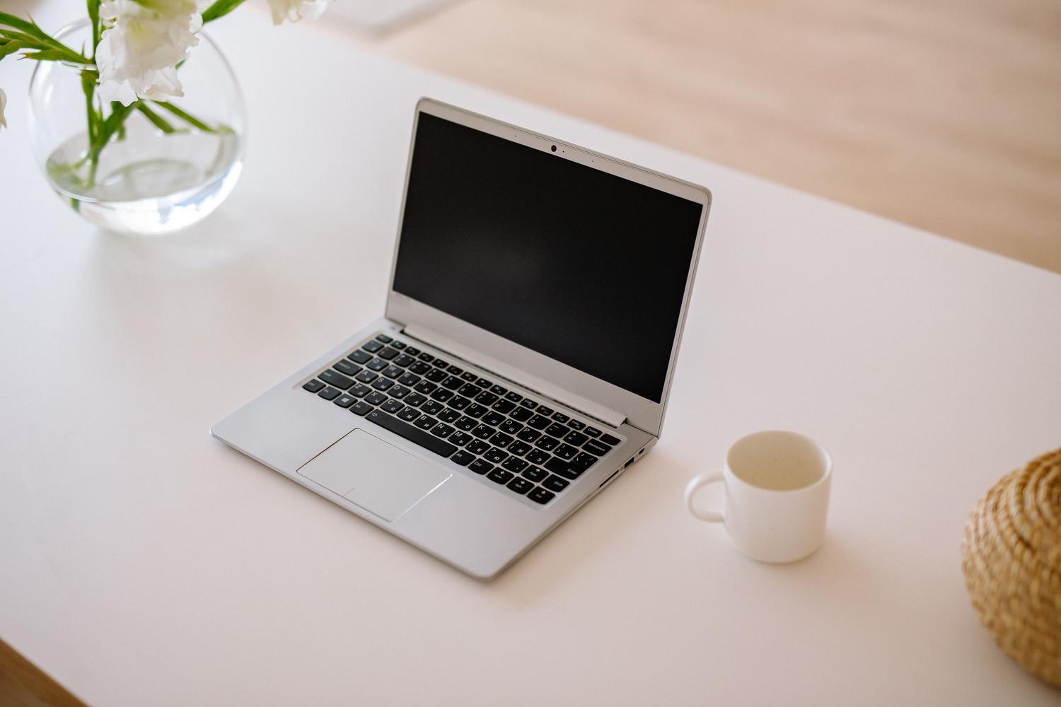 Espacio de trabajo minimalista con un ordenador portátil abierto sobre una mesa blanca, representando la limpieza visual y el diseño rompedor de Arc Browser.