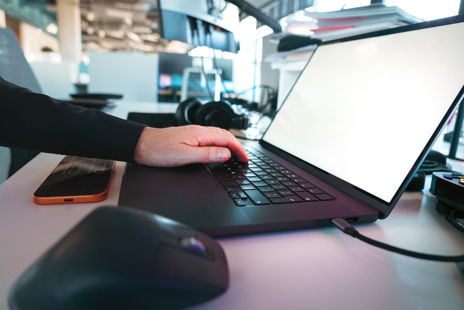 Primer plano de manos utilizando un teclado de portátil en un entorno de oficina tecnológica