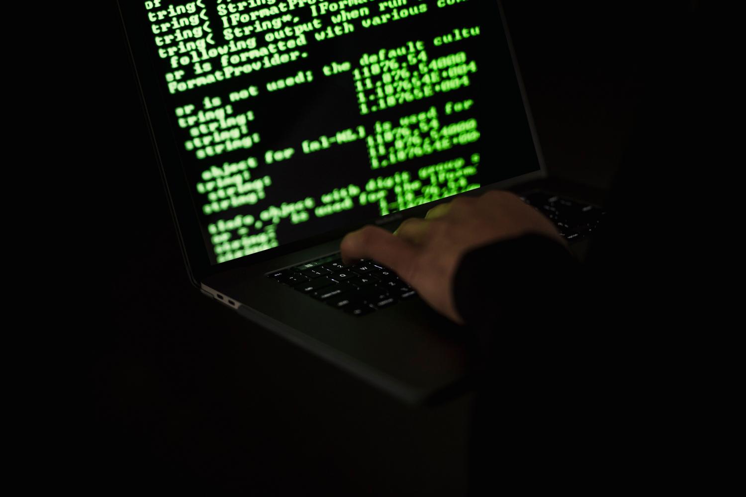 Representación visual de un hacker trabajando en la oscuridad con código verde en pantalla