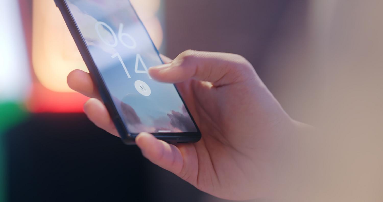 Persona utilizando el sensor de huellas dactilares para desbloquear un smartphone.