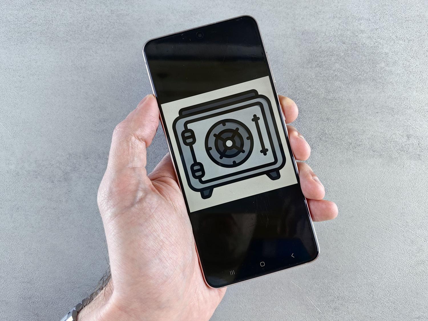 Smartphone mostrando un icono de caja fuerte en la pantalla, representando una Carpeta Segura o aplicación de privacidad.