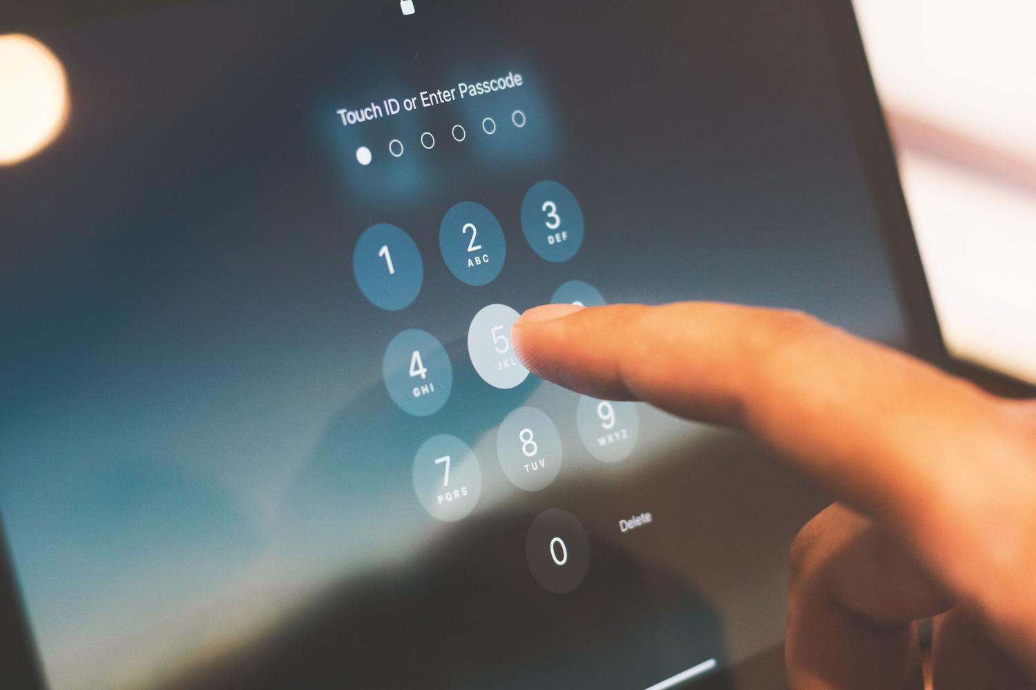 Mano introduciendo un código PIN en la pantalla de seguridad de un dispositivo móvil.