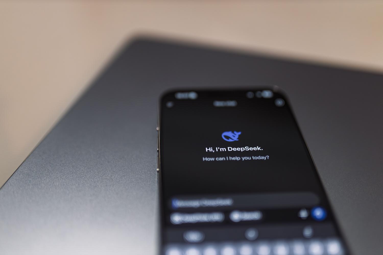 Primer plano de un smartphone con una interfaz de asistente de IA sobre un portátil, ilustrando la integración de Copilot.