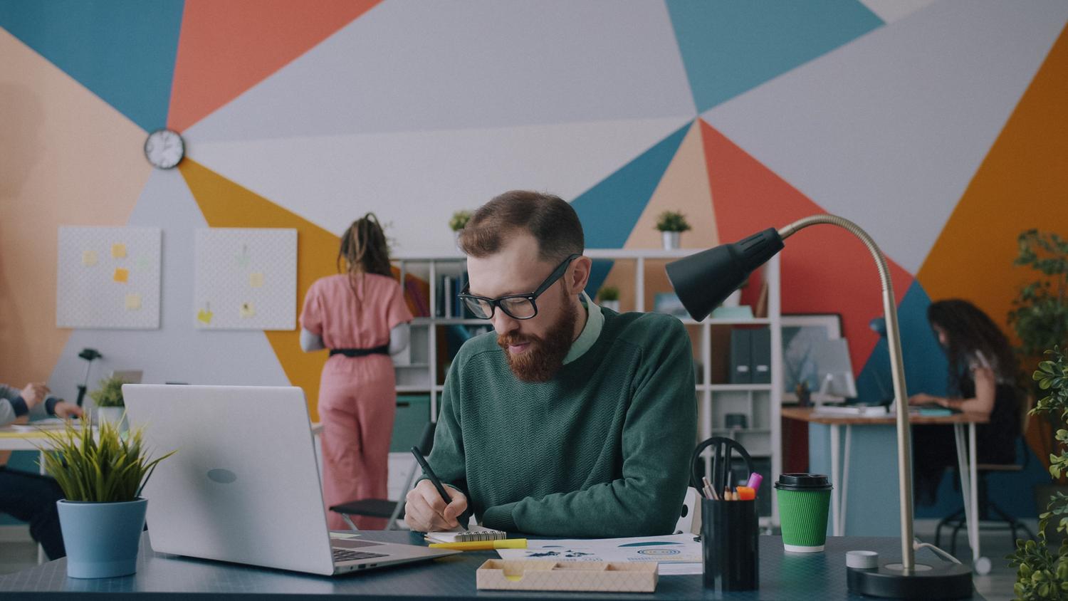 Diseñador joven trabajando en un espacio creativo analizando datos, reflejando la gestión eficiente de la información.