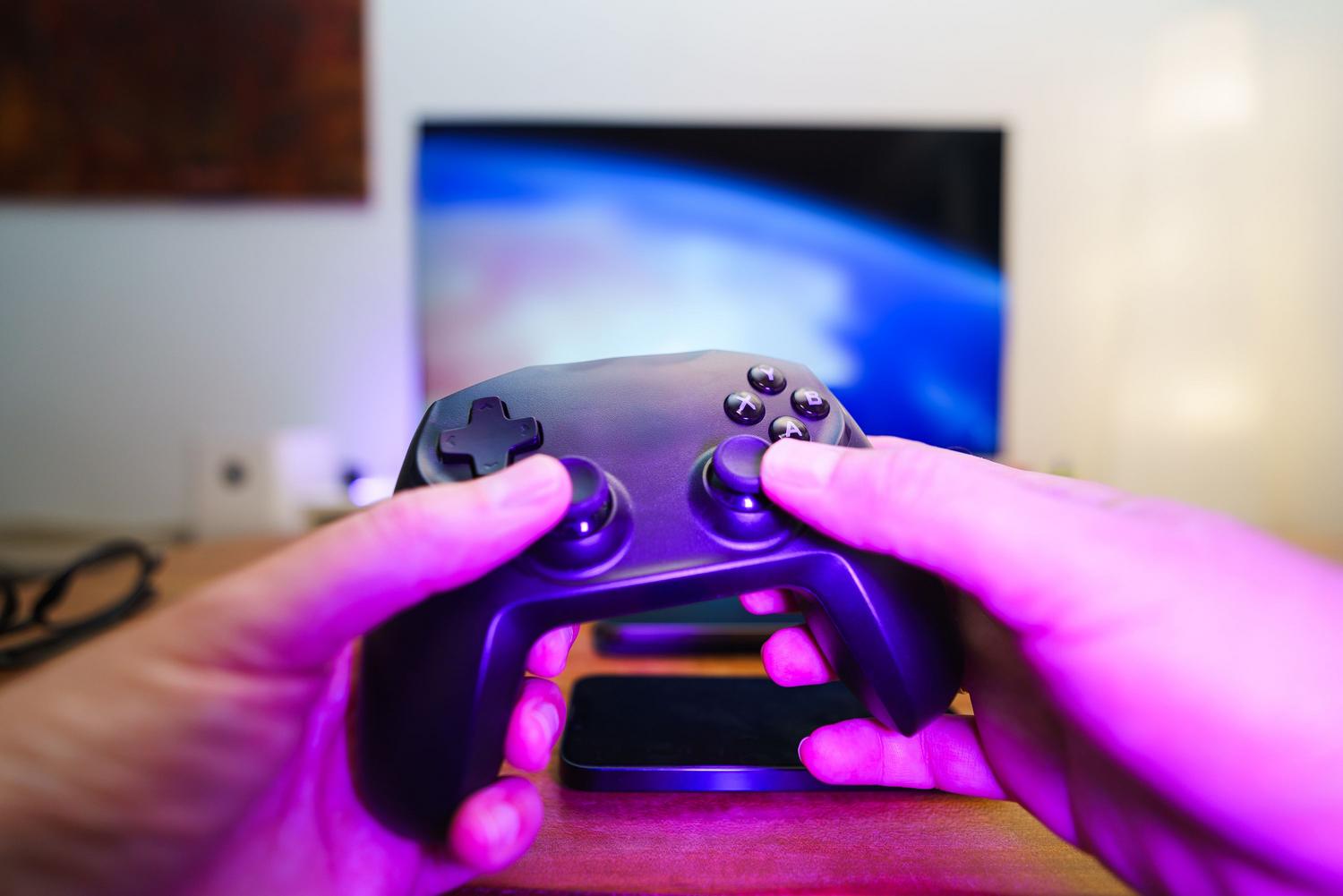 Primer plano de un mando de videojuegos físico junto a un smartphone, ilustrando la comparativa entre mandos reales y virtuales para Google TV.