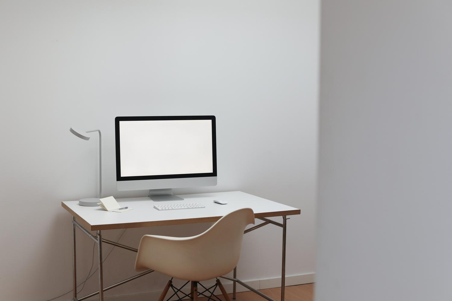 Espacio de trabajo moderno y minimalista con un ordenador sobre una mesa blanca, contexto perfecto para la productividad digital.