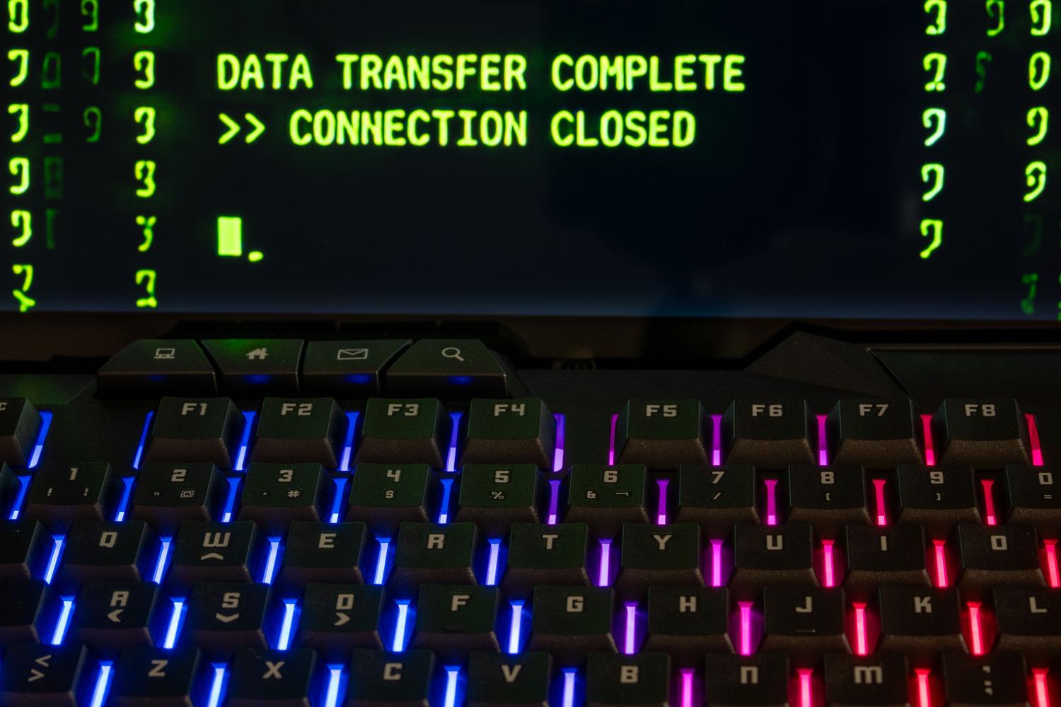 Teclado mecánico con iluminación RGB y una pantalla que muestra la finalización de una transferencia de datos, aportando un toque tecnológico moderno al artículo.