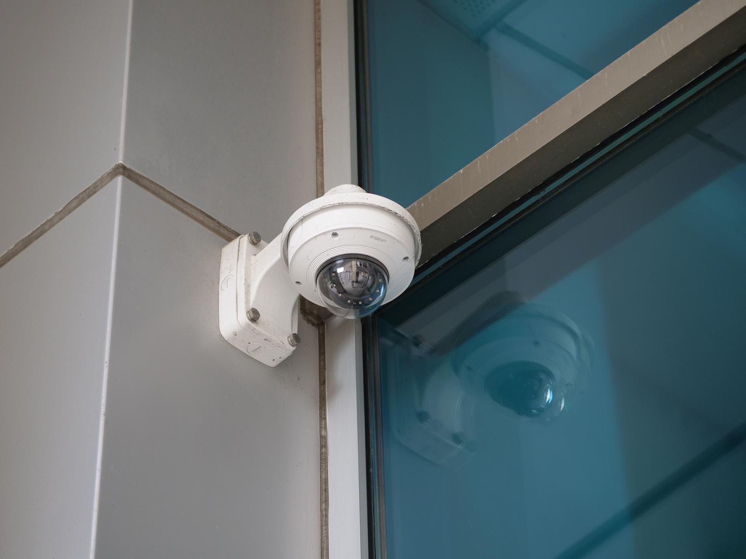 Primer plano de una cámara de seguridad en la esquina de un edificio moderno, ilustrando la omnipresencia de las cámaras IP.