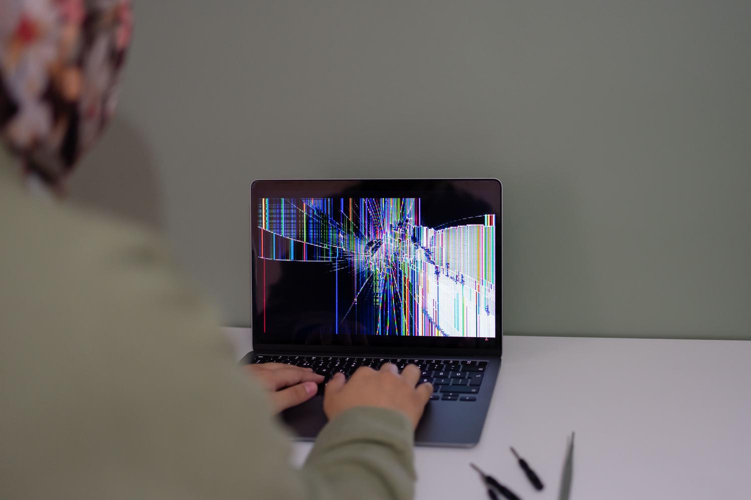 Persona utilizando un portátil con la pantalla rota, ilustrando fallos de hardware o software críticos.