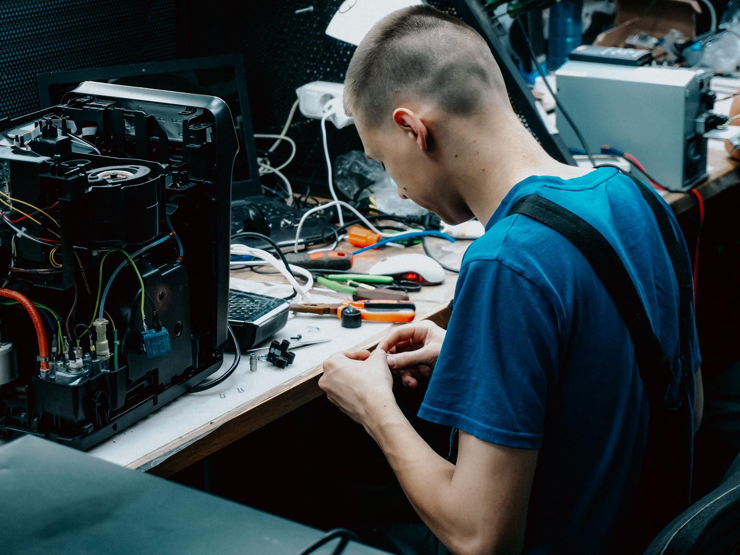Técnico especializado reparando un dispositivo electrónico en un taller profesional.