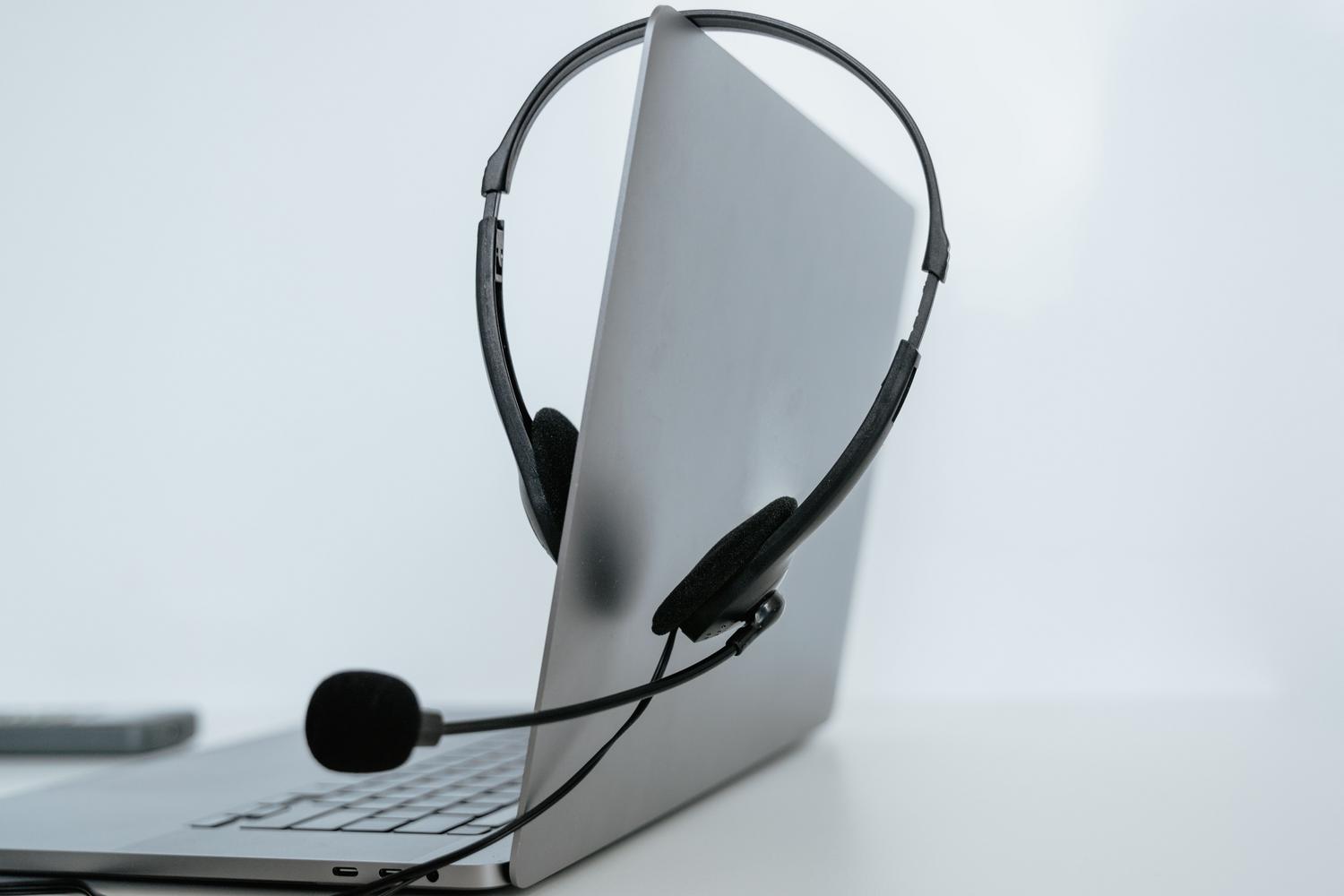 Primer plano de un portátil con auriculares, simbolizando el teletrabajo y el soporte remoto