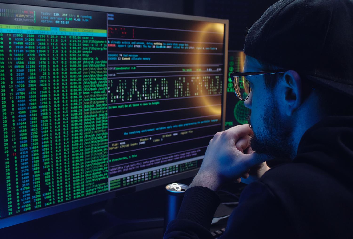 Analista de seguridad revisando logs y código en monitores, representando el análisis forense con Sysmon.