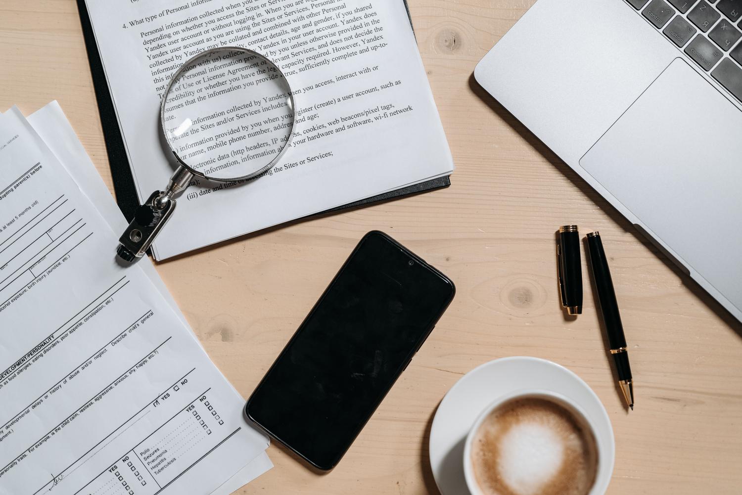 Vista cenital de un escritorio con documentos, portátil y café, ilustrando la organización y gestión de archivos PDF.