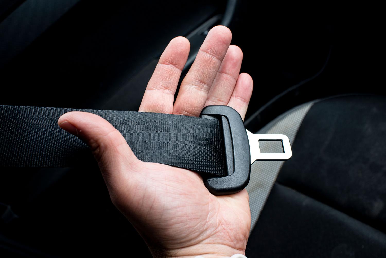 Primer plano de una mano sujetando el cinturón de seguridad, elemento fundamental de la seguridad pasiva.