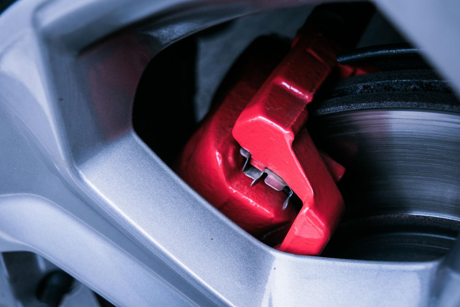 Detalle de un disco de freno y pinza roja de un coche, representando los sistemas de seguridad activa como el ABS.