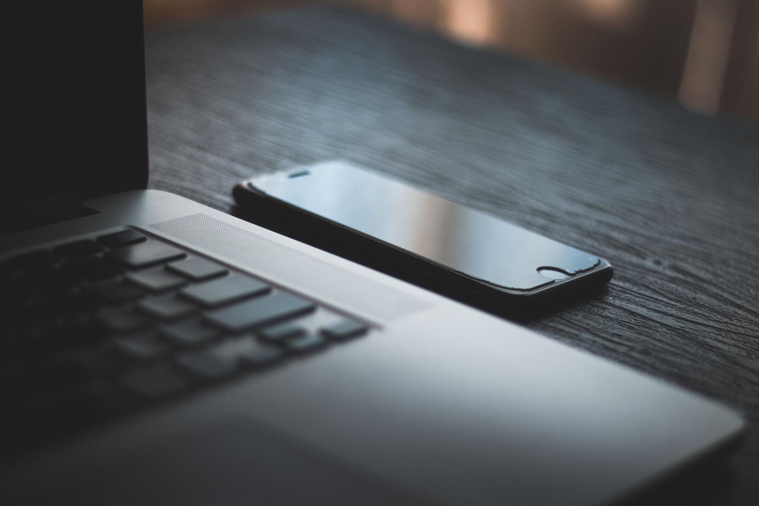 Detalle de un portátil y un smartphone sobre una mesa de madera, evocando la conectividad y el almacenamiento digital contemporáneo.