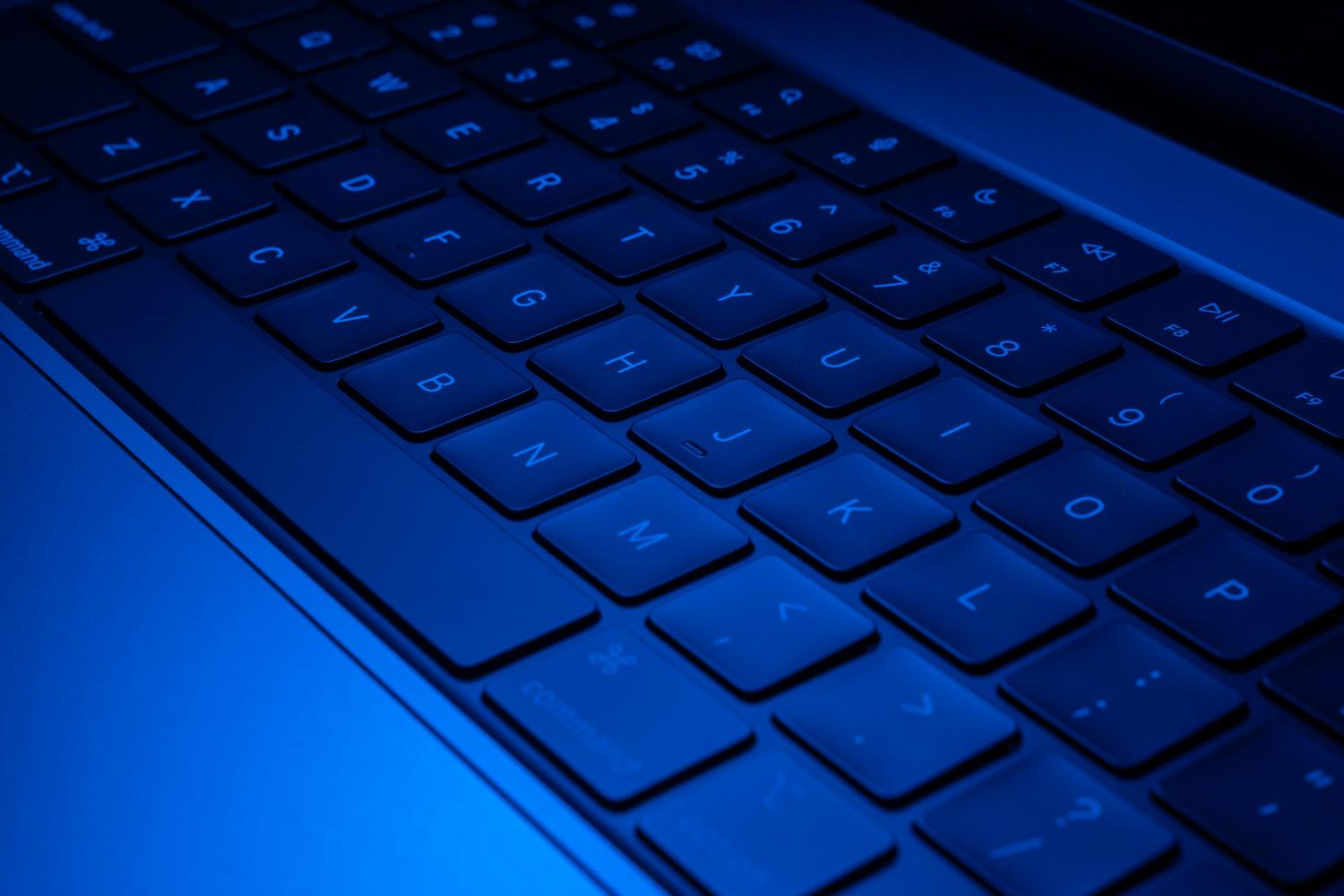 Teclado de portátil con retroiluminación azul, evocando configuraciones de sistema y tecnología avanzada.