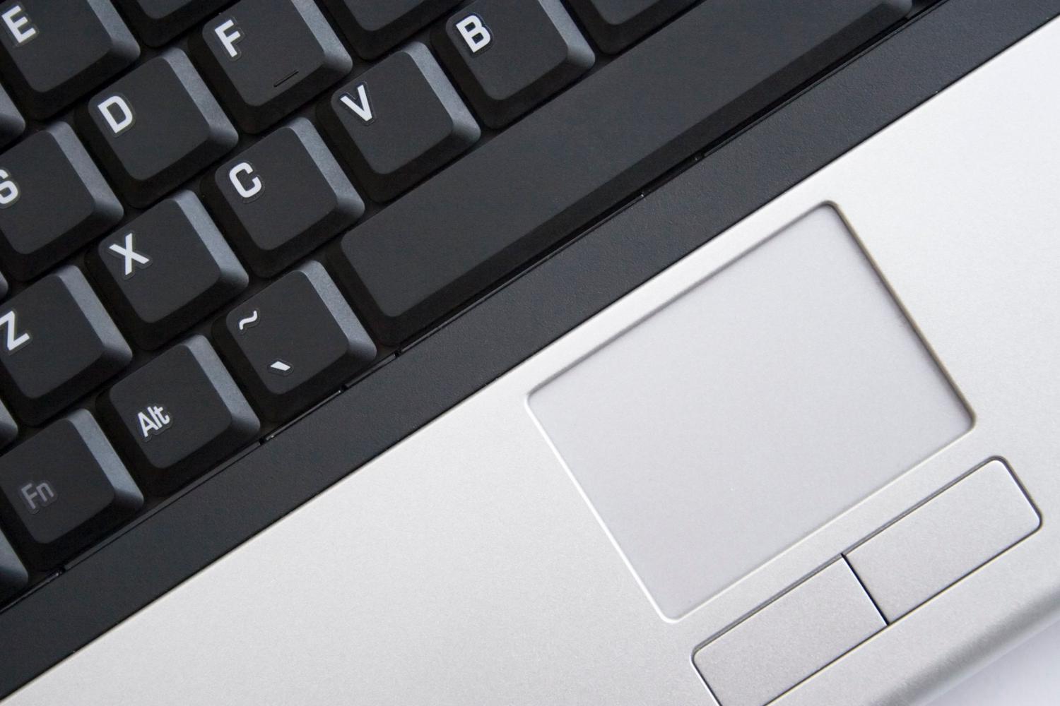 Primer plano de un teclado y un touchpad de portátil, ilustrando la gestión de periféricos de entrada.
