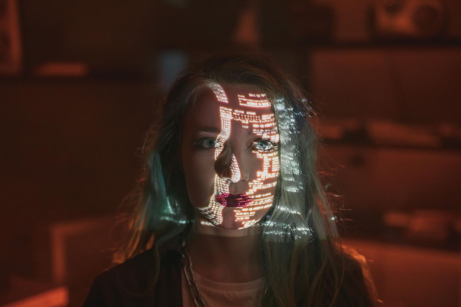 Retrato de una mujer con código binario proyectado sobre su rostro, ilustrando la inteligencia artificial y el procesamiento de datos faciales.