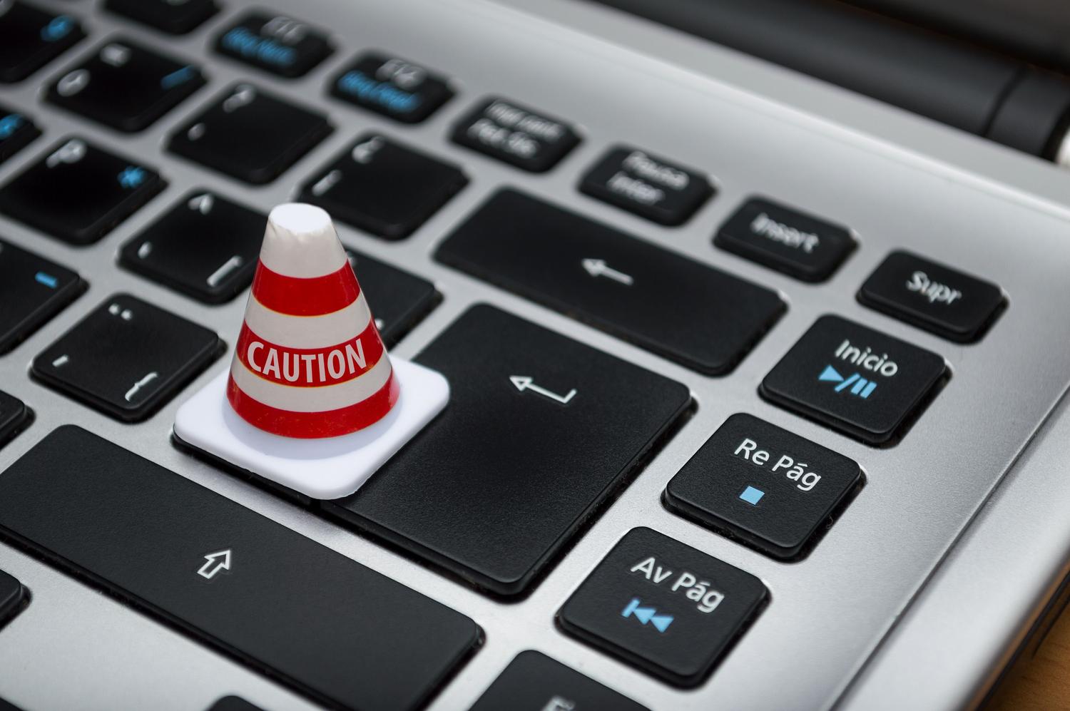 Un pequeño cono de precaución sobre un teclado, simbolizando la cautela, el sentido común y el mantenimiento activo de la seguridad del PC.