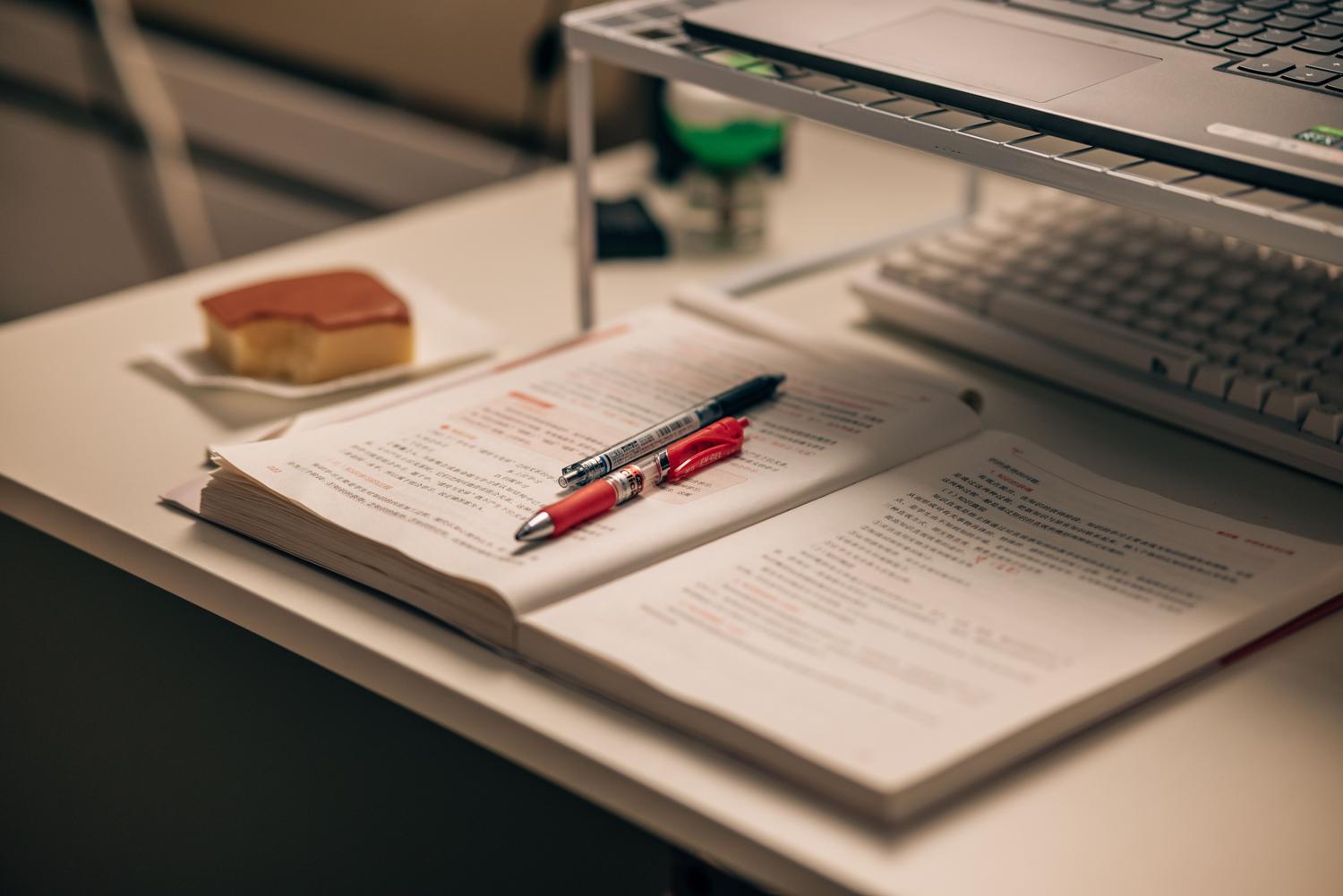 Materiales de estudio para la certificación CISSP: libro abierto con anotaciones, resaltadores y un portátil en un escritorio.