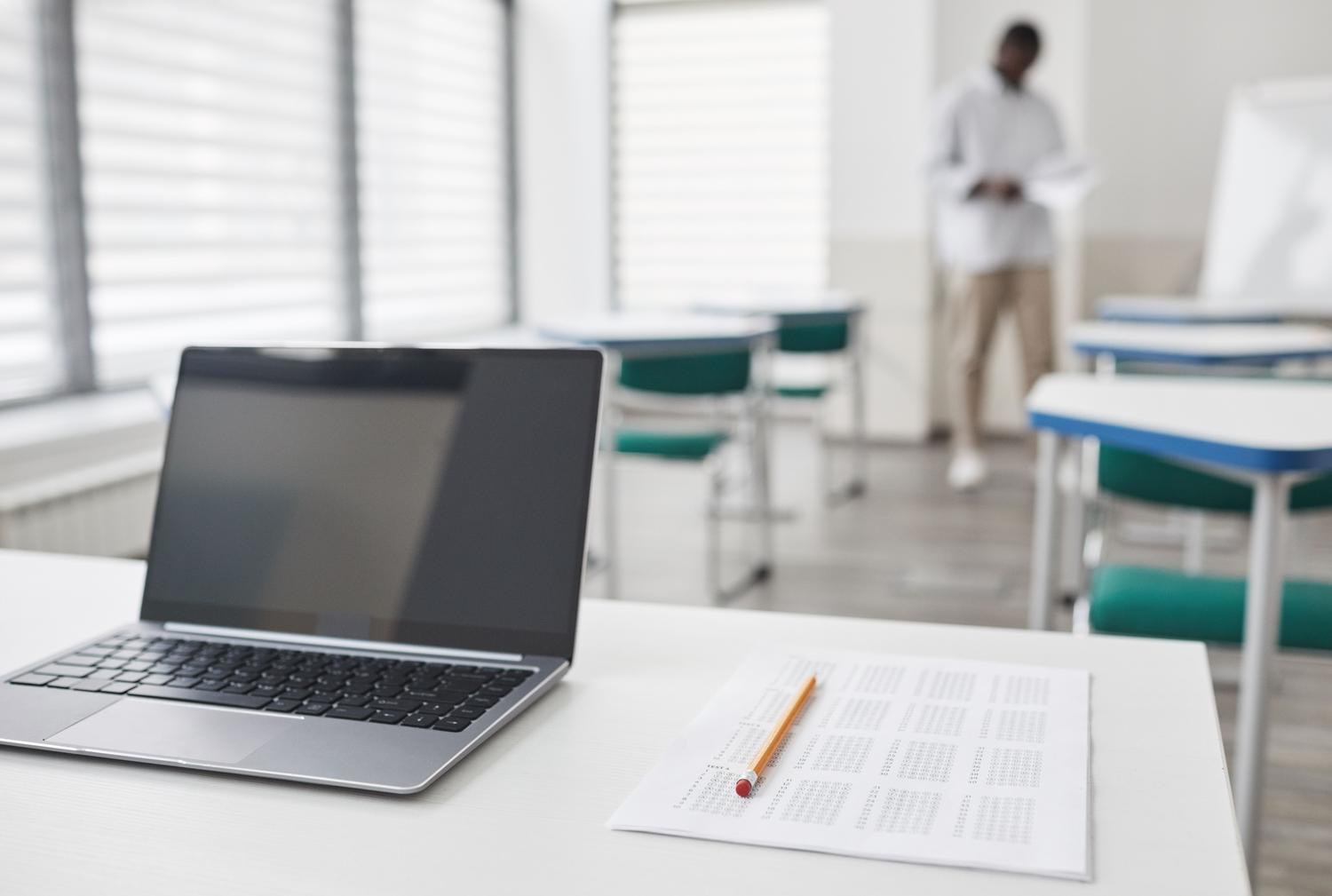 Entorno de examen de certificación profesional con un ordenador portátil y una hoja de respuestas sobre la mesa.