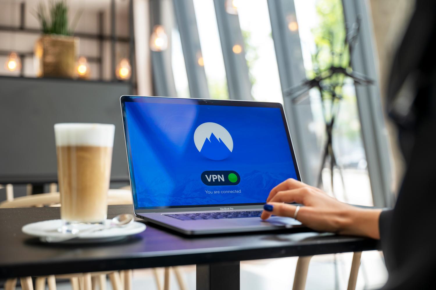 Uso de conexión VPN en un ordenador portátil desde una cafetería para acceso remoto seguro.