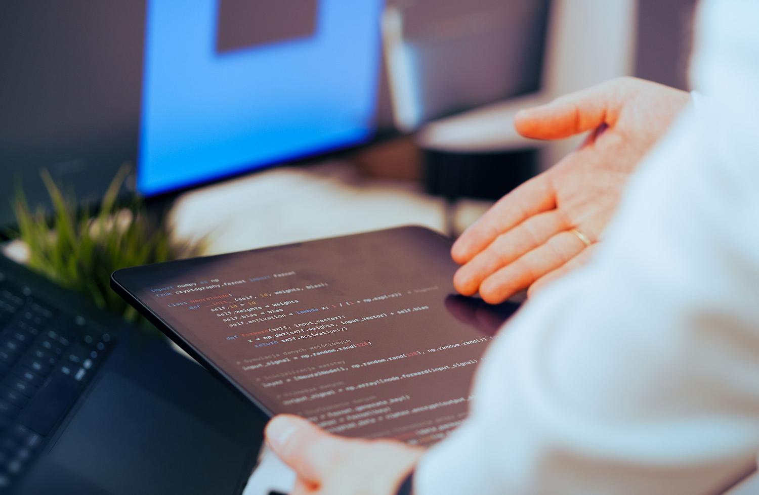 Desarrollador analizando código de redes neuronales en una tablet para la planificación estratégica del software