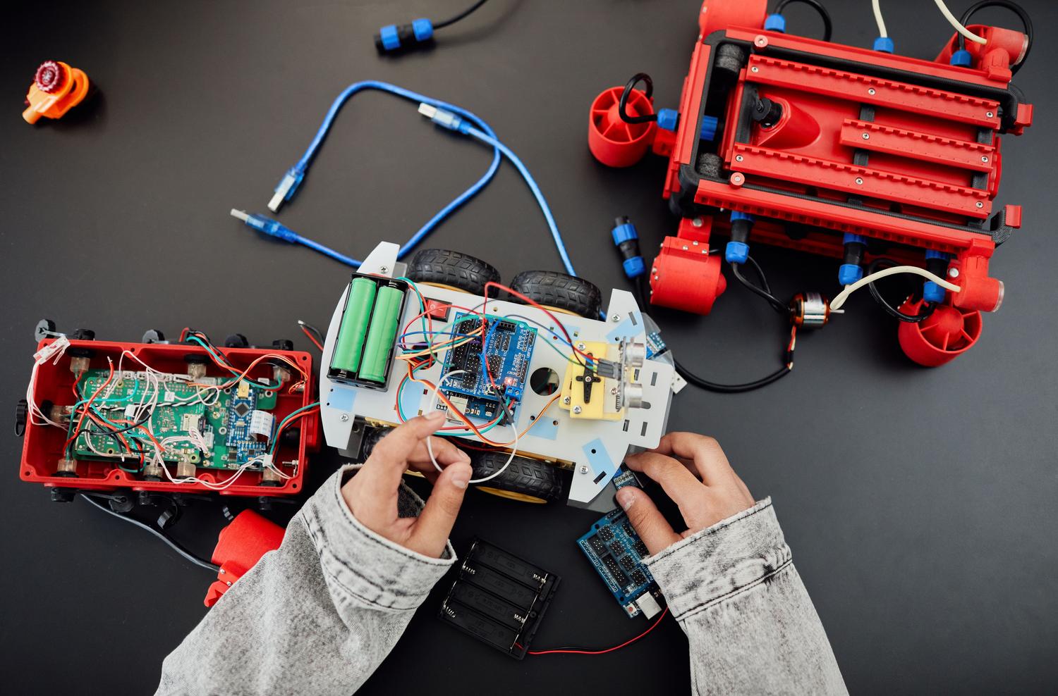 Manos de un estudiante trabajando en el montaje de un robot móvil, representando el enfoque Maker y STEAM.