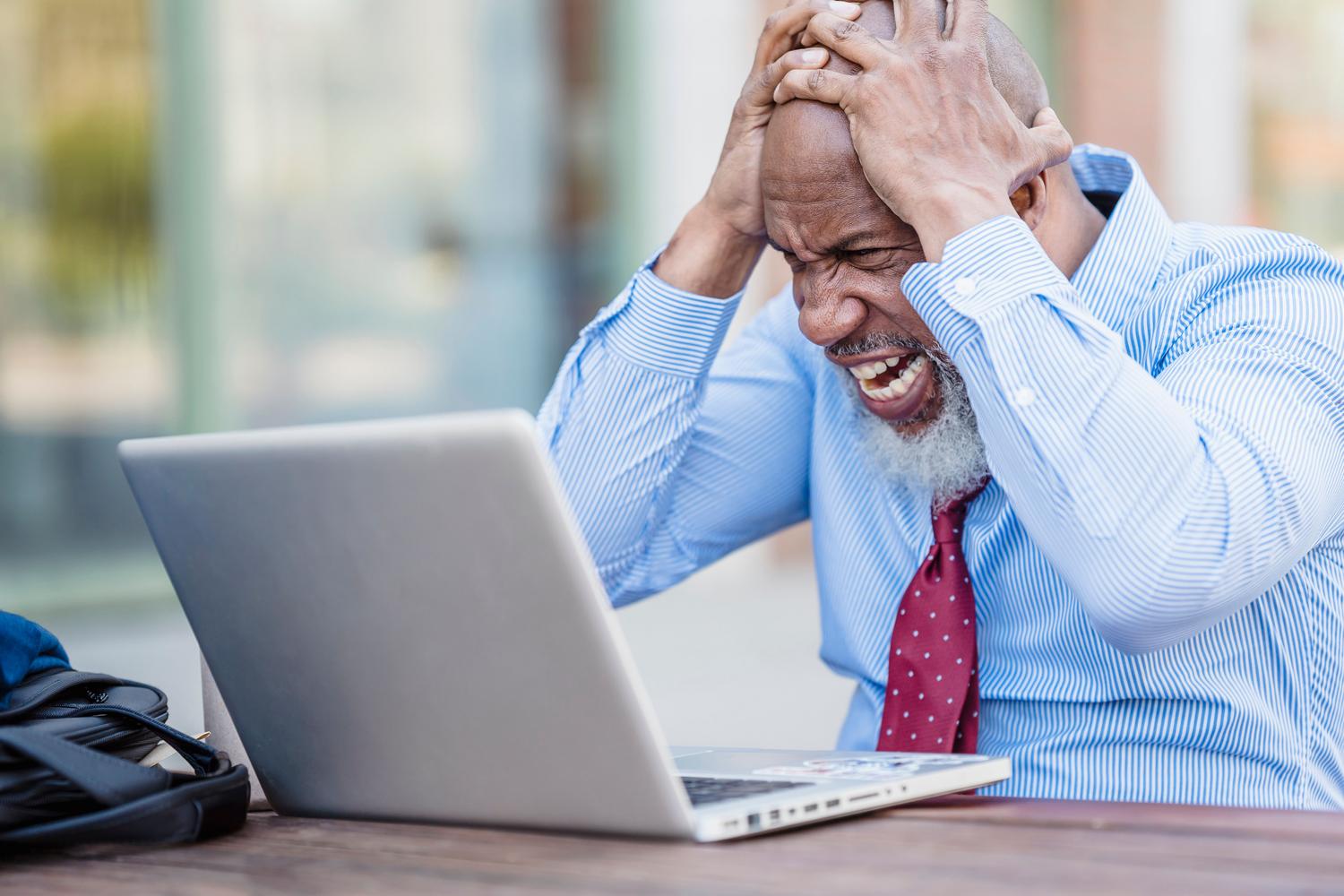 Hombre profesional frustrado frente a su portátil, representando el estrés de encontrarse con un error de actualización de Windows.