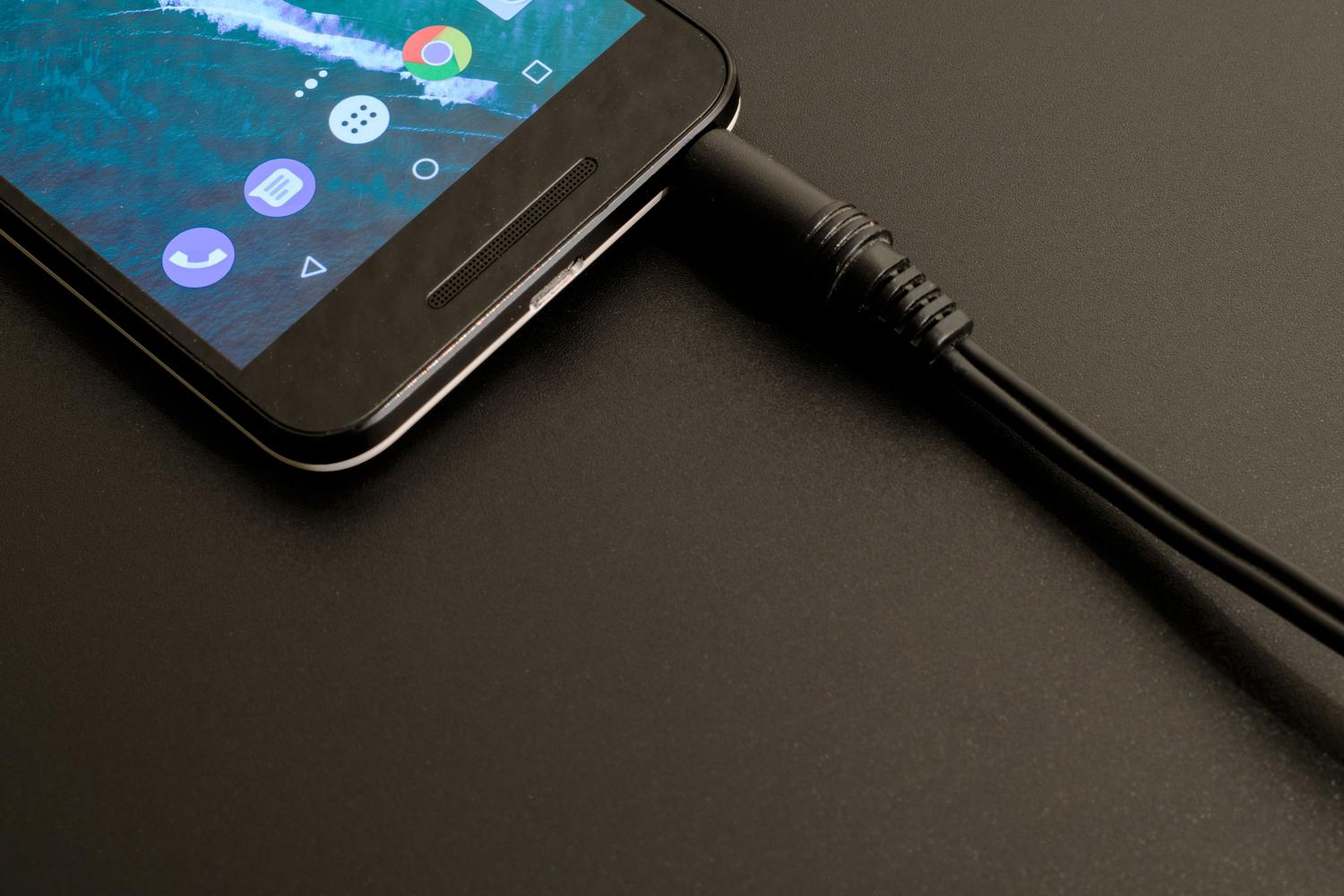 Primer plano de un smartphone conectado a un cable USB, ilustrando las conexiones físicas del dispositivo.
